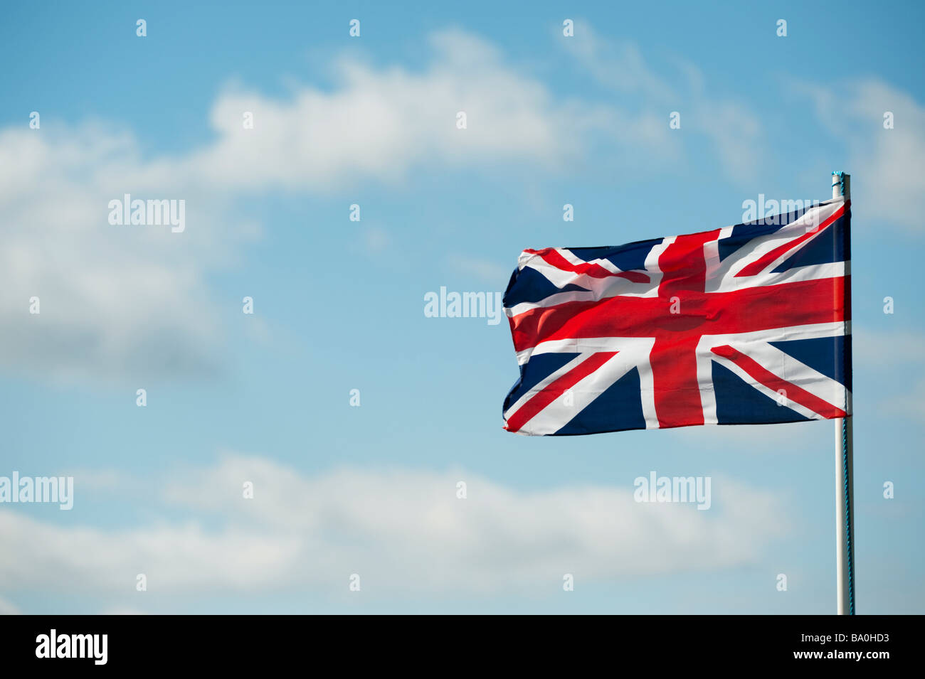 Union Jack flag flottant au vent contre un bleu ciel nuageux. UK Banque D'Images