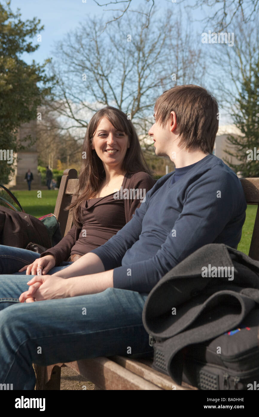 Jeune couple parler et vous détendre dans un parc public en Angleterre, Royaume-Uni Banque D'Images