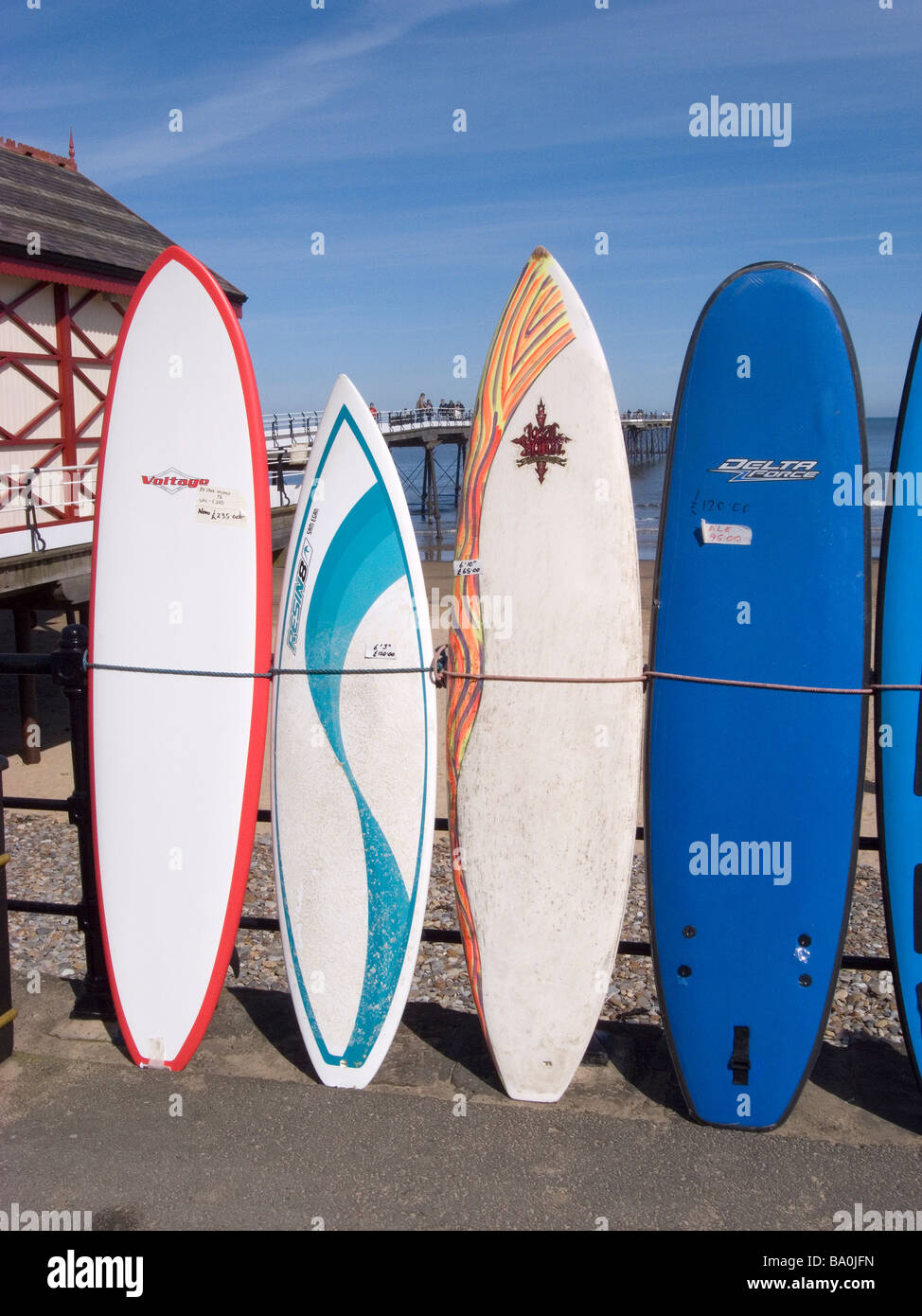 Planches de surf de mer liée contre la rambarde, à l'extérieur de la boutique par la jetée à Dharamsala, Cleveland, UK Banque D'Images