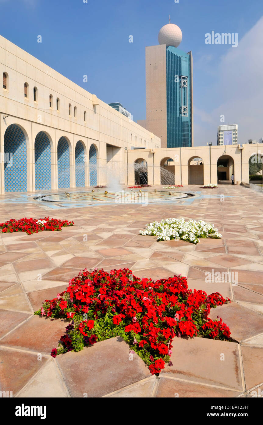 La Fondation culturelle d'Abu Dhabi cour pavée avec fontaine et fleurs pétunia rouge Banque D'Images