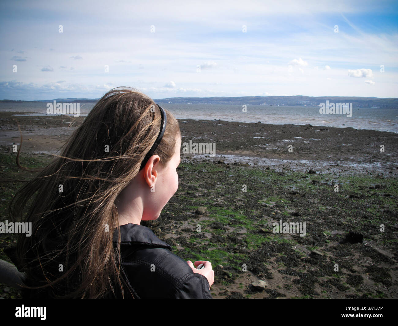 Pre teen girl face à la mer sur l'estran exposés à marée basse Banque D'Images