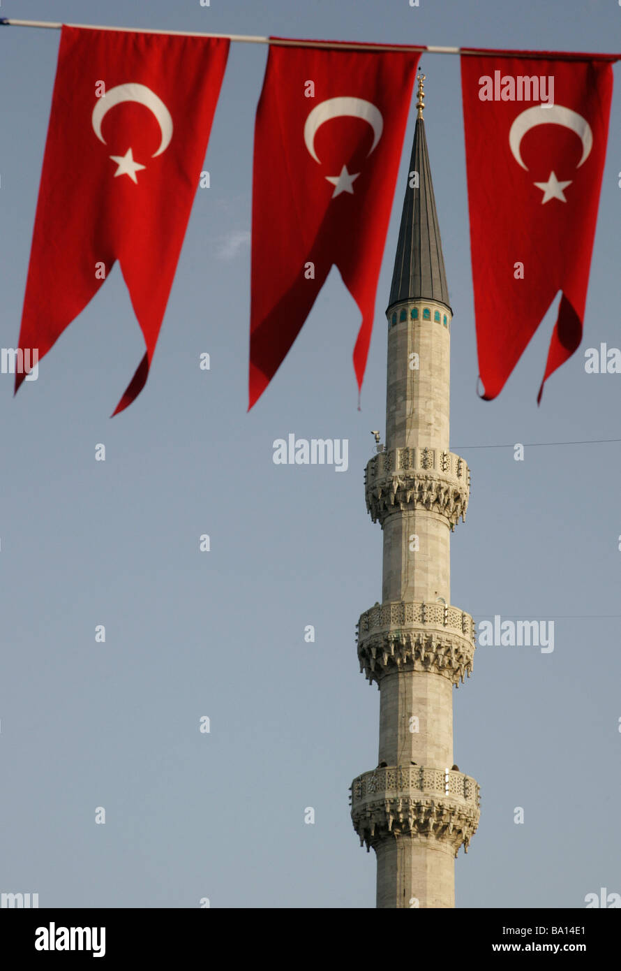 Un minaret d'une mosquée est représenté derrière 3 fanions rouges montrant l'étoile et le croissant turc ensign à Istanbul Turquie Banque D'Images