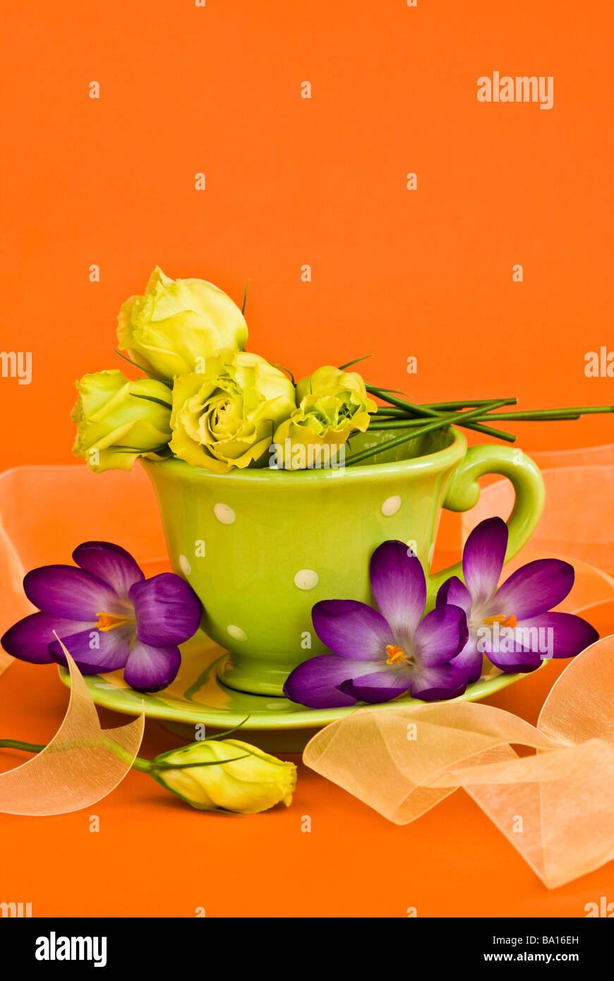 Arrangement décoratif de verre avec des fleurs et ruban sur fond orange clair Banque D'Images