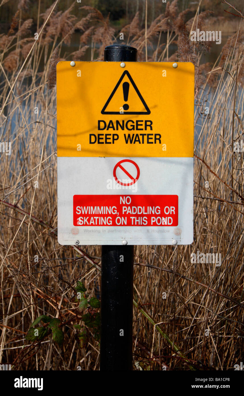Un 'Danger' de l'eau profonde sign post à côté d'un étang dans les lacs du parc, Yacine Boukabous Pays Yacine Boukabous, Middlesex, Royaume-Uni. Banque D'Images