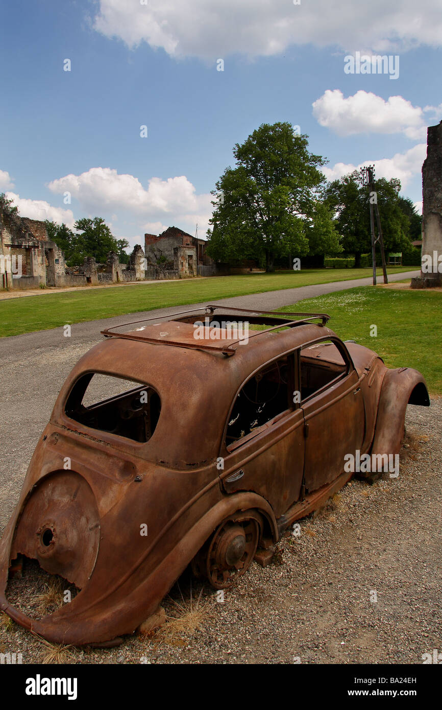Une voiture détruite dans le village martyr d'Oradour sur Glane. Ciel bleu profond avec des nuages au-delà. Limousin, France. Banque D'Images