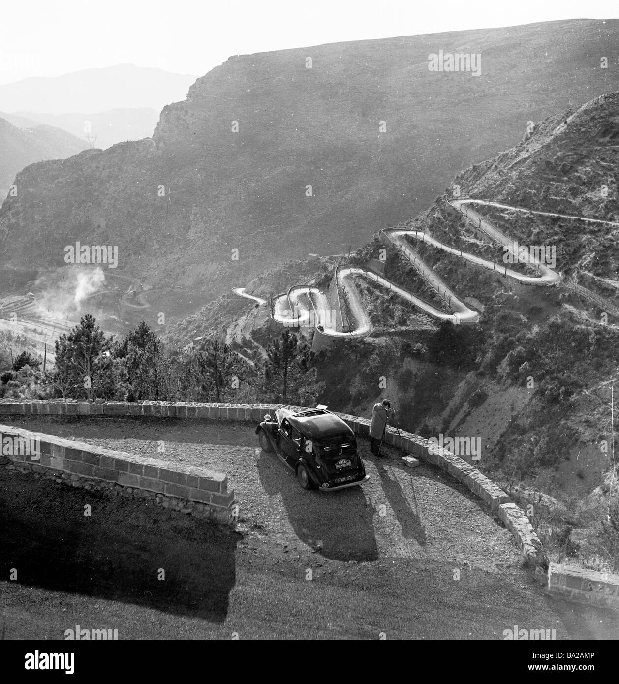 1952, historique, un caméraman de film prend des images du col de Braus, une route sinueuse dans les Alpes, en France, qui fait partie du Rallye Monte-Carlo. Banque D'Images