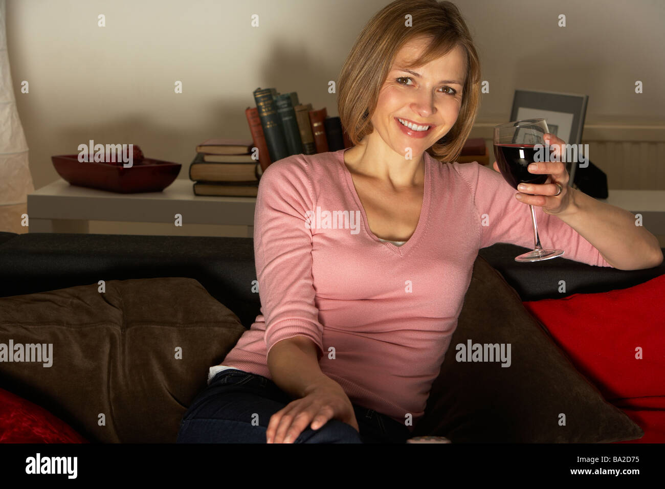 Woman Relaxing avec verre de vin en regardant la télévision Banque D'Images