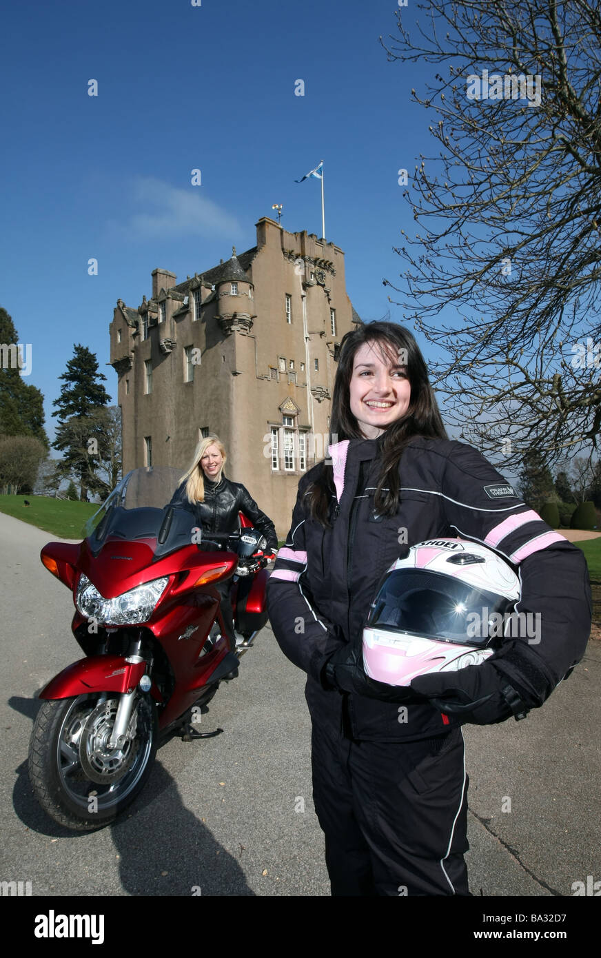 Deux femmes motocyclistes posant avec prêt de porter des vêtements protecteurs à l'emplacement de château écossais Banque D'Images