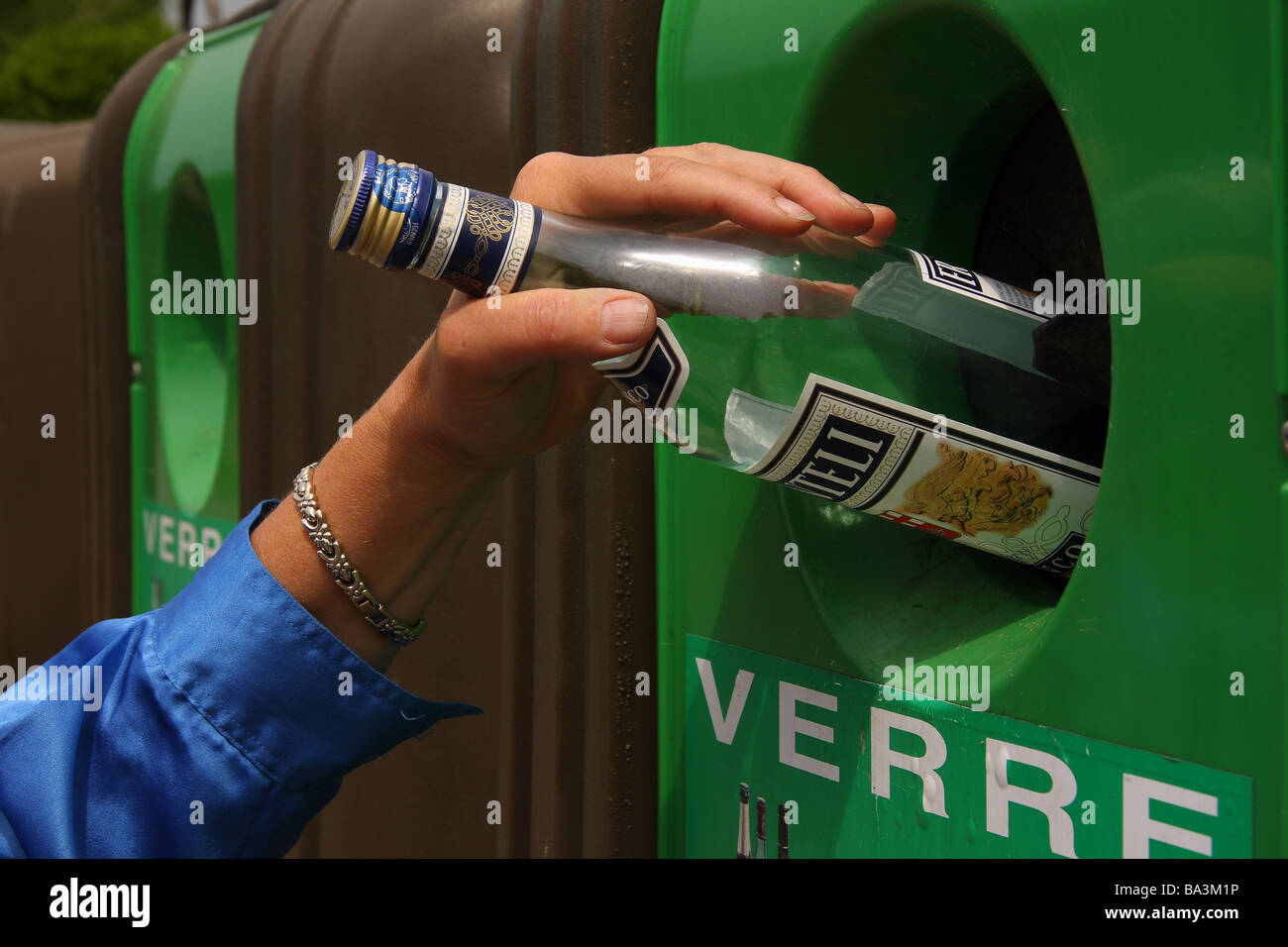 Quelqu'un mettre une bouteille en verre dans un bac de recyclage Limousin France Banque D'Images
