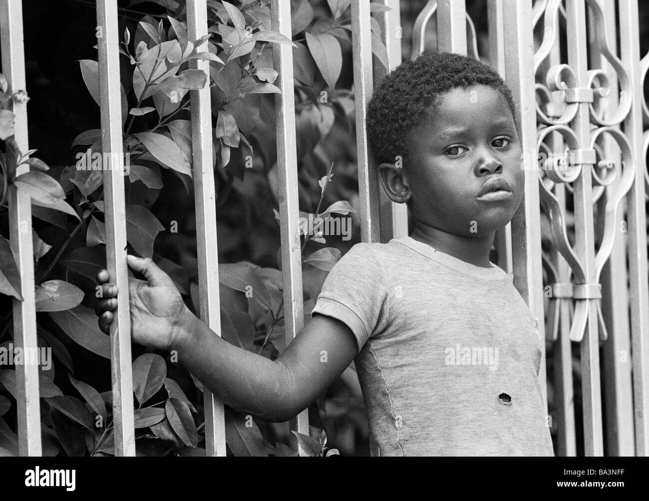 Années 70, photo en noir et blanc, les gens, la pauvreté, le garçon s'appuie contre une barre de fer, tatty teeshirt, âgés de 8 à 12 ans, au Brésil, Minas Gerais, Belo Horizonte Banque D'Images