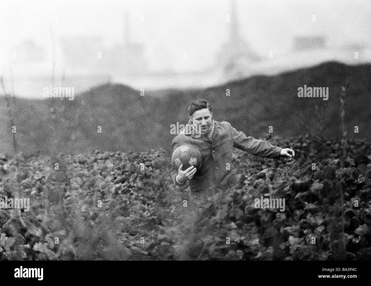 Années 70, photo en noir et blanc, les gens, involontaire d'un football a été coups de pied dans un tas, l'homme grimpe sur le tas et prend la balle à le ramener sur le terrain de football, match de football, l'humour, âgés de 35 à 45 ans, de la Ruhr, Rhénanie du Nord-Westphalie Banque D'Images