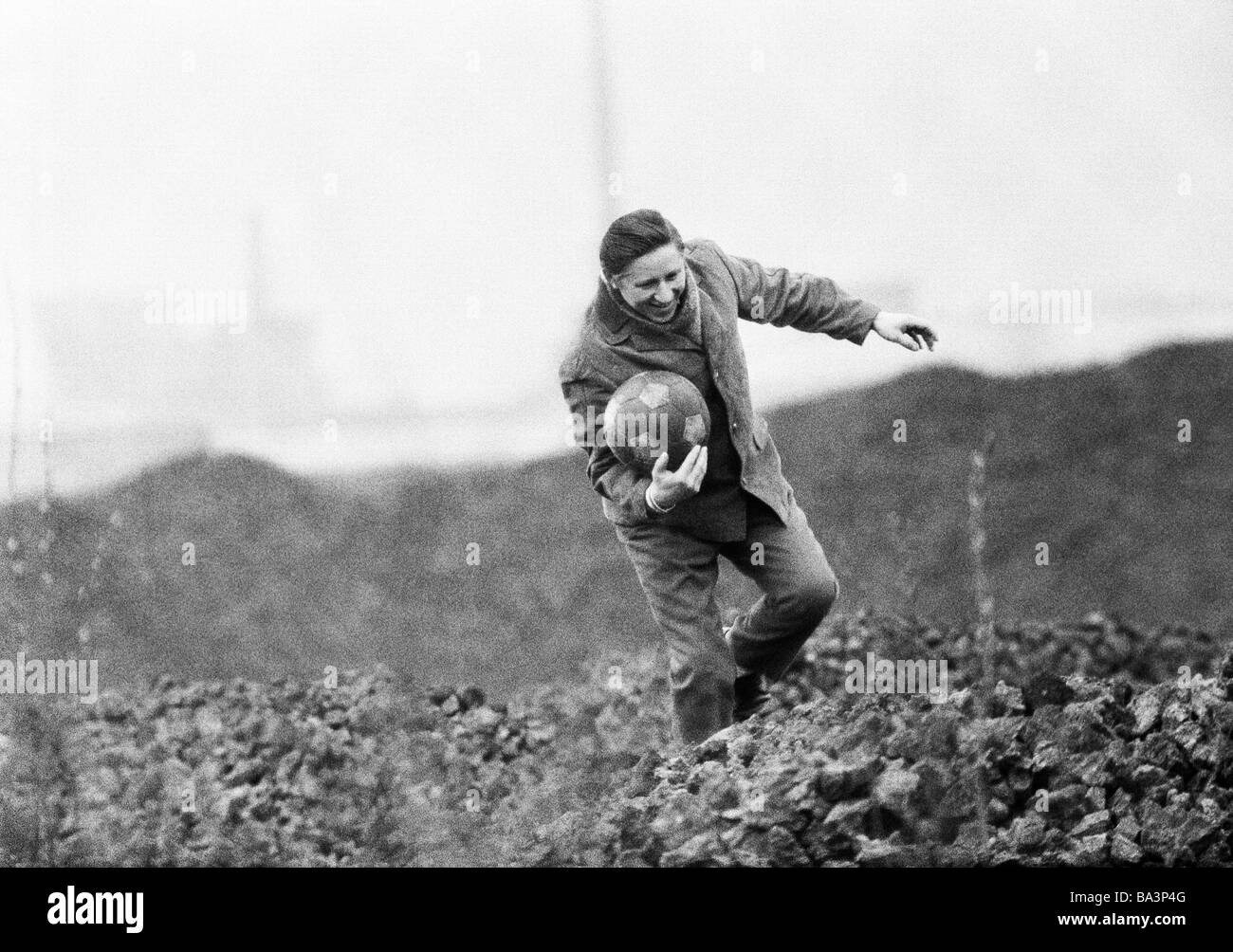 Années 70, photo en noir et blanc, les gens, involontaire d'un football a été coups de pied dans un tas, l'homme grimpe sur le tas et prend la balle à le ramener sur le terrain de football, match de football, l'humour, âgés de 35 à 45 ans, de la Ruhr, Rhénanie du Nord-Westphalie Banque D'Images