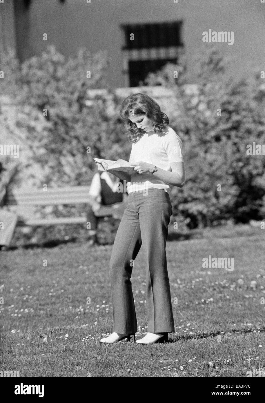 Années 70, photo en noir et blanc, personnage, jeune femme debout sur une prairie de lire un livre, pulli, pantalons, parc, âgés de 25 à 30 ans, à ce moment-Yougoslavie, la Yougoslavie, aujourd'hui la Slovénie, Ljubljana Banque D'Images