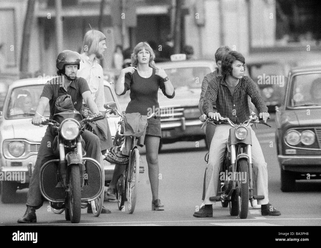 Années 70, photo en noir et blanc, le trafic routier, le trafic de différents utilisateurs en attente aux feux rouges, moto, scooter, vélo, voitures de tourisme, les jeunes hommes, jeune femme, adolescents, âgés de 18 à 35 ans, Pays-Bas, Amsterdam Banque D'Images