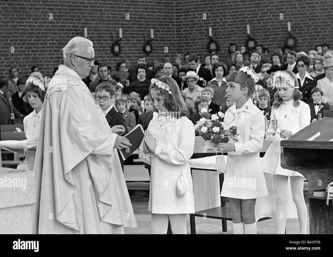 Années 70, photo en noir et blanc, la religion, le christianisme, la première communion, les filles et les garçons avec un prêtre pendant la messe eucharistique, adorateurs, âgés de 8 à 12 ans, de 55 à 65 ans Banque D'Images