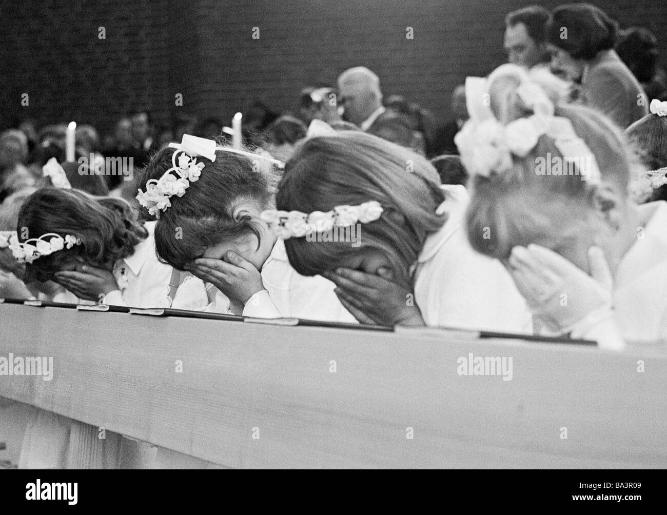 Années 70, photo en noir et blanc, la religion, le christianisme, la Première Communion, quatre filles prie au banc après avoir reçu la Sainte Communion, âgés de 8 à 12 ans, Babette Banque D'Images