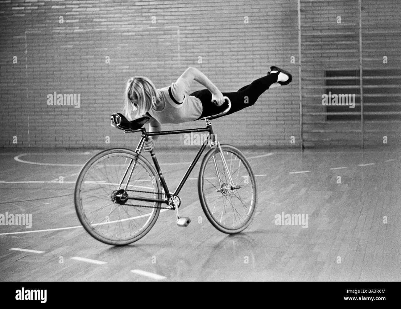 Années 70, photo en noir et blanc, sports, randonnée à vélo, randonnée à vélo artistique, jeune fille effectue un exercice sur un vélo, sports hall, âgés de 14 à 18 ans, D-Oberhausen, D-Oberhausen-Osterfeld, Ruhr, Rhénanie du Nord-Westphalie Banque D'Images