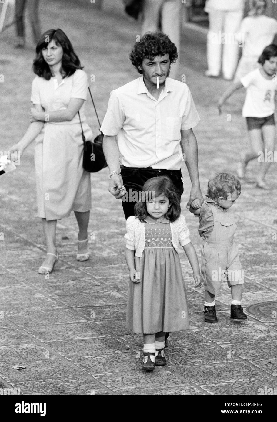 Années 1980, photo en noir et blanc, les gens, la famille, les parents prennent une marche avec la fille et le fils, les touristes, l'homme avec la cigarette, âgés de 30 à 40 ans, femme marche après, âgés de 25 à 35 ans, fille, âgés de 3 à 5 ans, garçon, âgés de 1 à 2 ans, l'Espagne, Îles Canaries, Tenerife, Puerto de la Cruz Banque D'Images