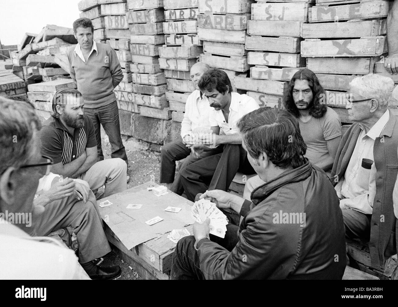 Années 1980, photo en noir et blanc, plusieurs pêcheurs dans le port de pêche de Puerto de la Cruz ont une pause et jouer aux cartes devant un lot de boîtes en bois, de 40 à 70 ans, l'Espagne, Îles Canaries, Tenerife Banque D'Images