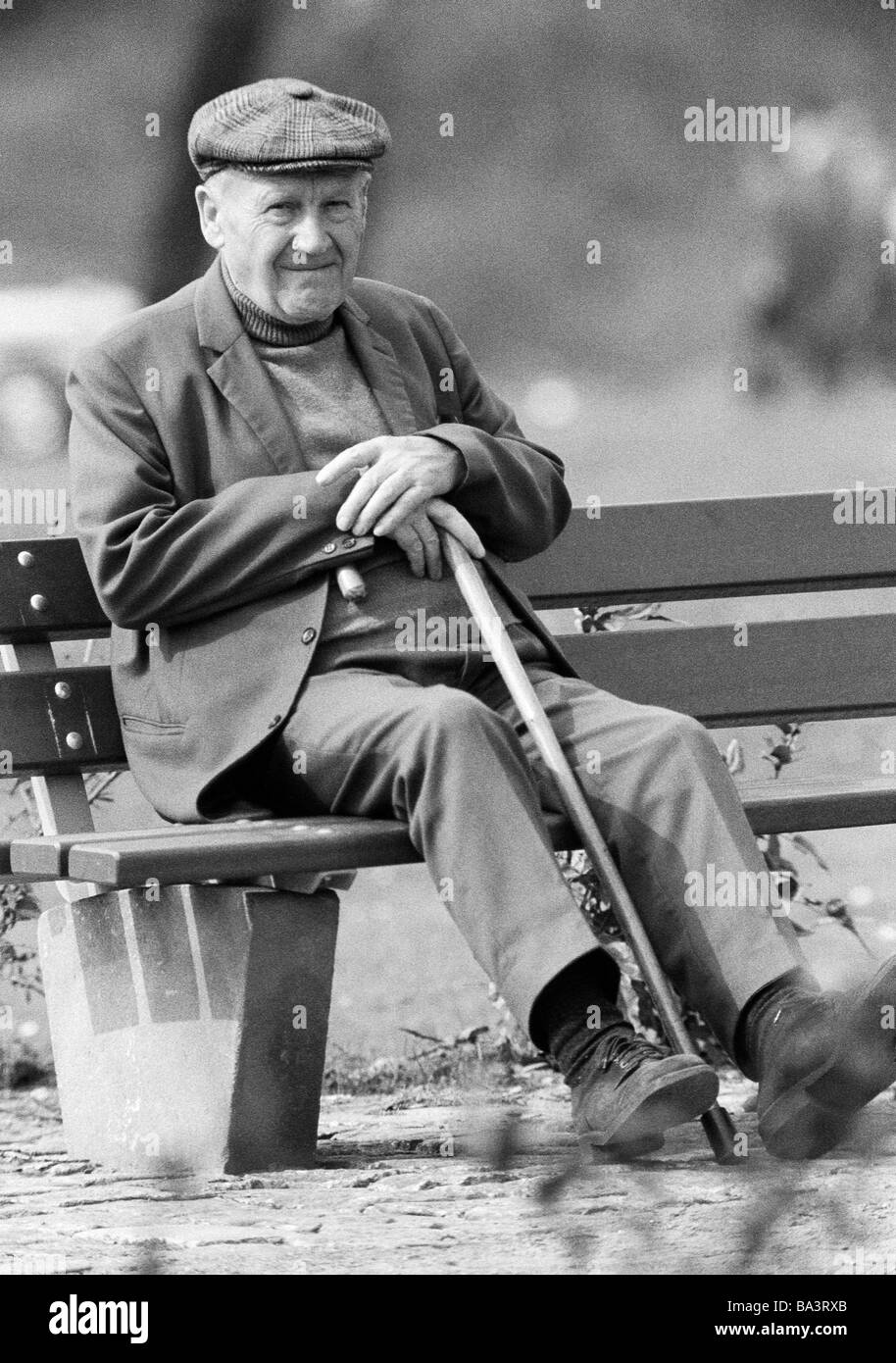 Années 70, photo en noir et blanc, les gens, les personnes âgées, homme plus âgé avec un bâton de marche est assis sur un banc, âgés de 70 à 80 ans Banque D'Images