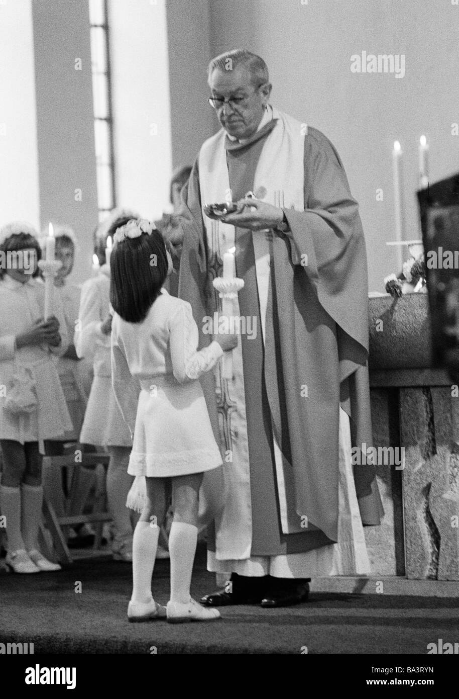 Années 70, photo en noir et blanc, la religion, le christianisme, Première Communion eucharistique, la messe, prêtre administre la Sainte Communion à une fille, âgés de 8 à 12 ans, de 60 à 70 ans, Andrea Banque D'Images