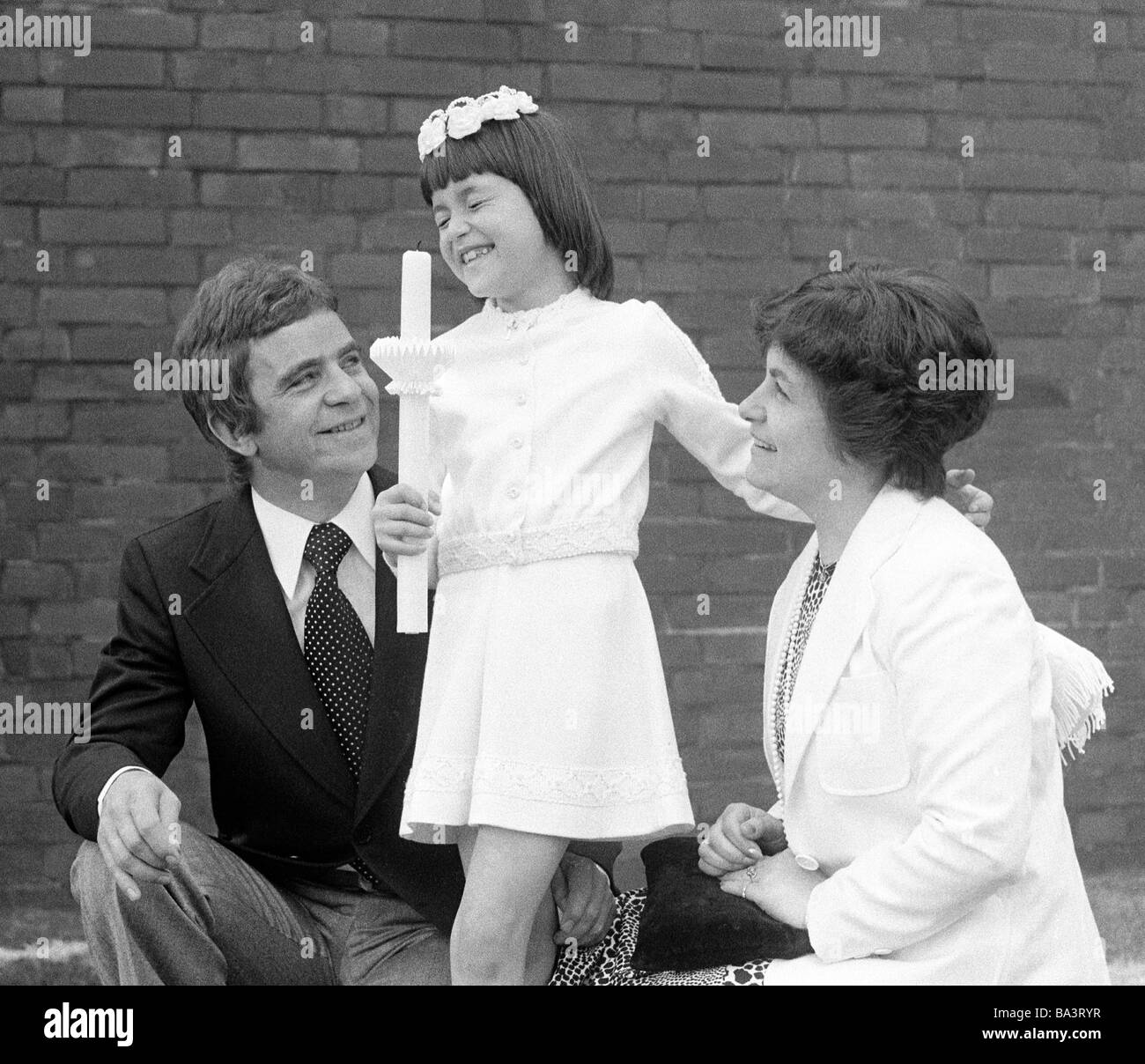 Années 70, photo en noir et blanc, la religion, le christianisme, Première Communion, girl porte une bougie, père et mère sont heureux, âgés de 8 à 12 ans, de 35 à 45 ans, Andrea, Doris, Fredi Banque D'Images