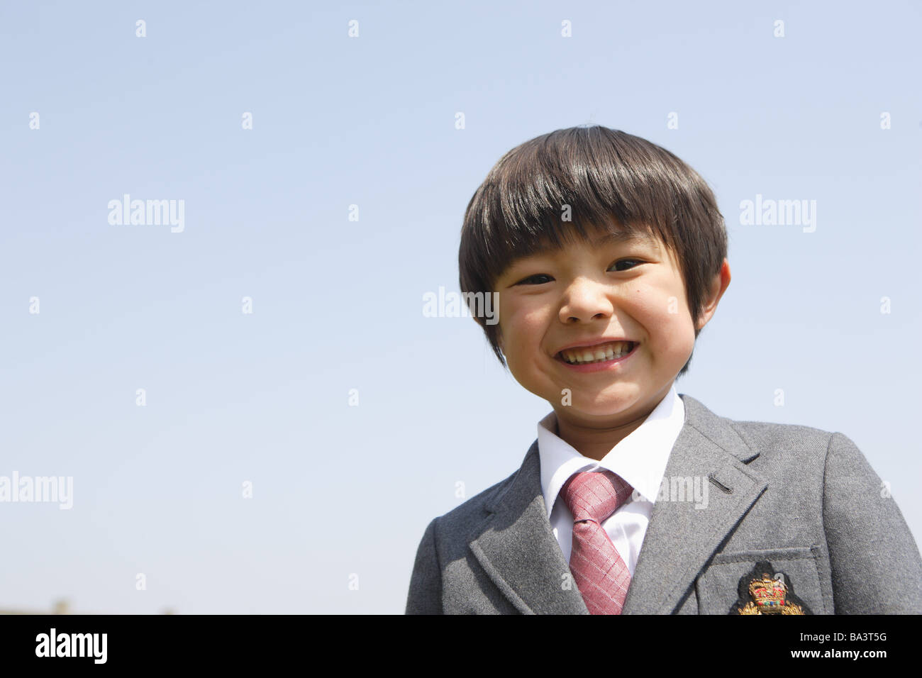 Écolier japonais smiling contre ciel clair Banque D'Images