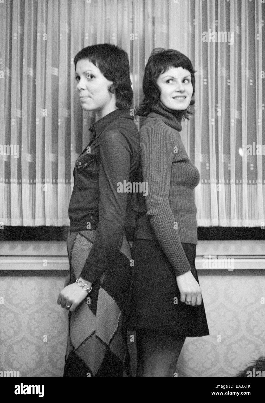 Années 70, photo en noir et blanc, les gens, les deux jeunes filles se tenir dos à dos contrôler leur hauteur de corps, blouse, jupe, minijupe, Gaby, Gabi, âgés de 18 à 22 ans Banque D'Images