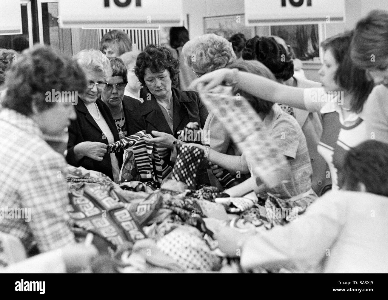 Années 70, photo en noir et blanc, les gens sur l'expédition shopping, clôture de la vente, plusieurs femmes recherchez les aubaines d'un tableau de charité Banque D'Images