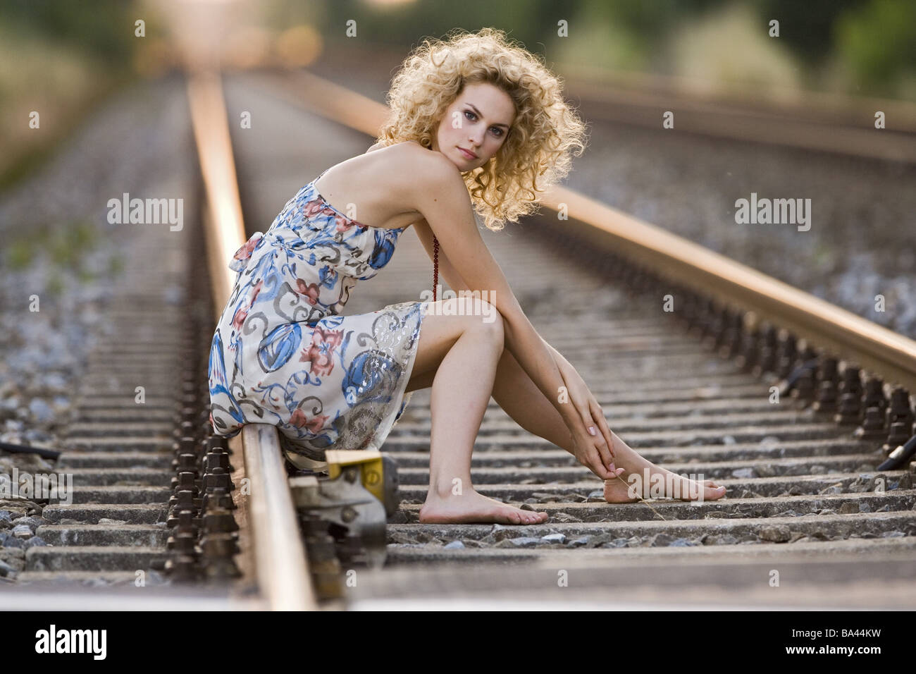 Jeune femme robe d'été pieds nus dans les rails de chemin de fer est assis  pensivement les séries de 20 à 30 ans robe boucles sérieusement caméra  regard Photo Stock - Alamy