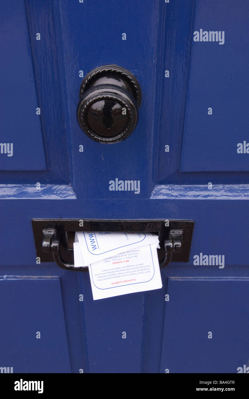 Dépliants de courrier indésirable qui sort d'une boîte aux lettres de la publicité peut-être une maison vide pour les cambrioleurs Banque D'Images