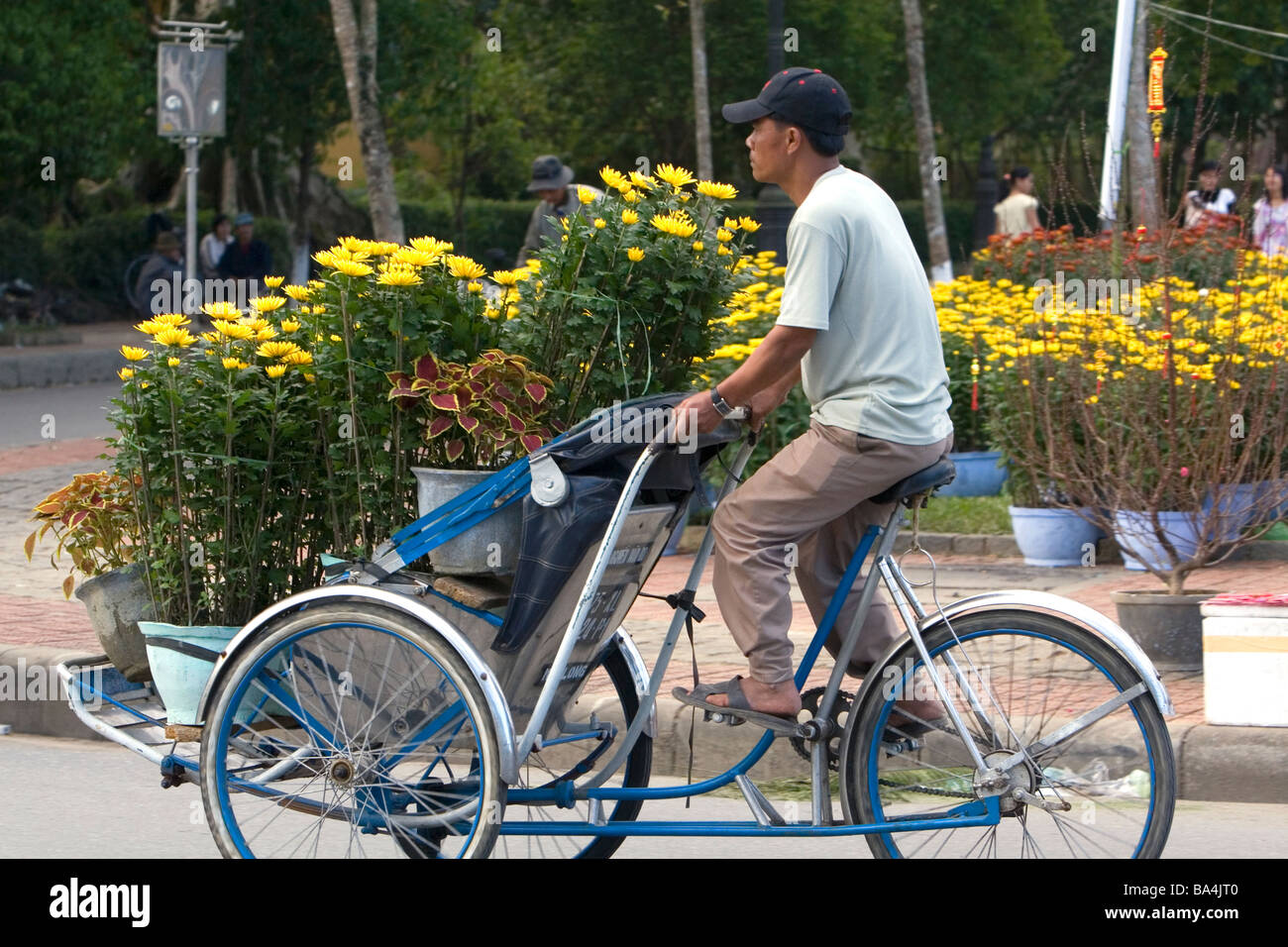 Transport de l'homme vietnamiens des fleurs sur un cyclo à Hue Vietnam Banque D'Images