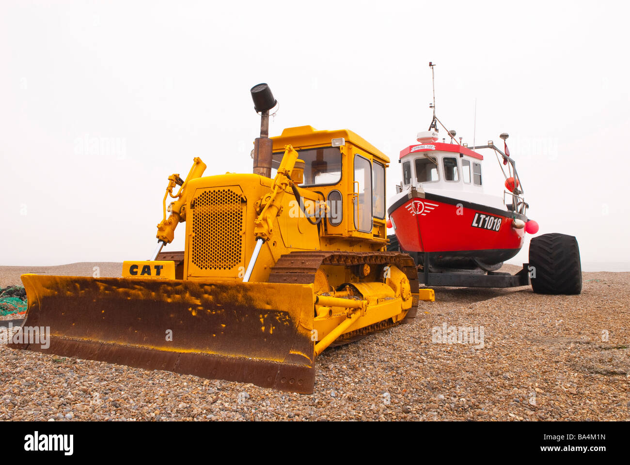 Un tracteur à chenilles Caterpillar bulldozer cat tirant un bateau de pêche sur la plage à Aldeburgh, Suffolk, UK Banque D'Images