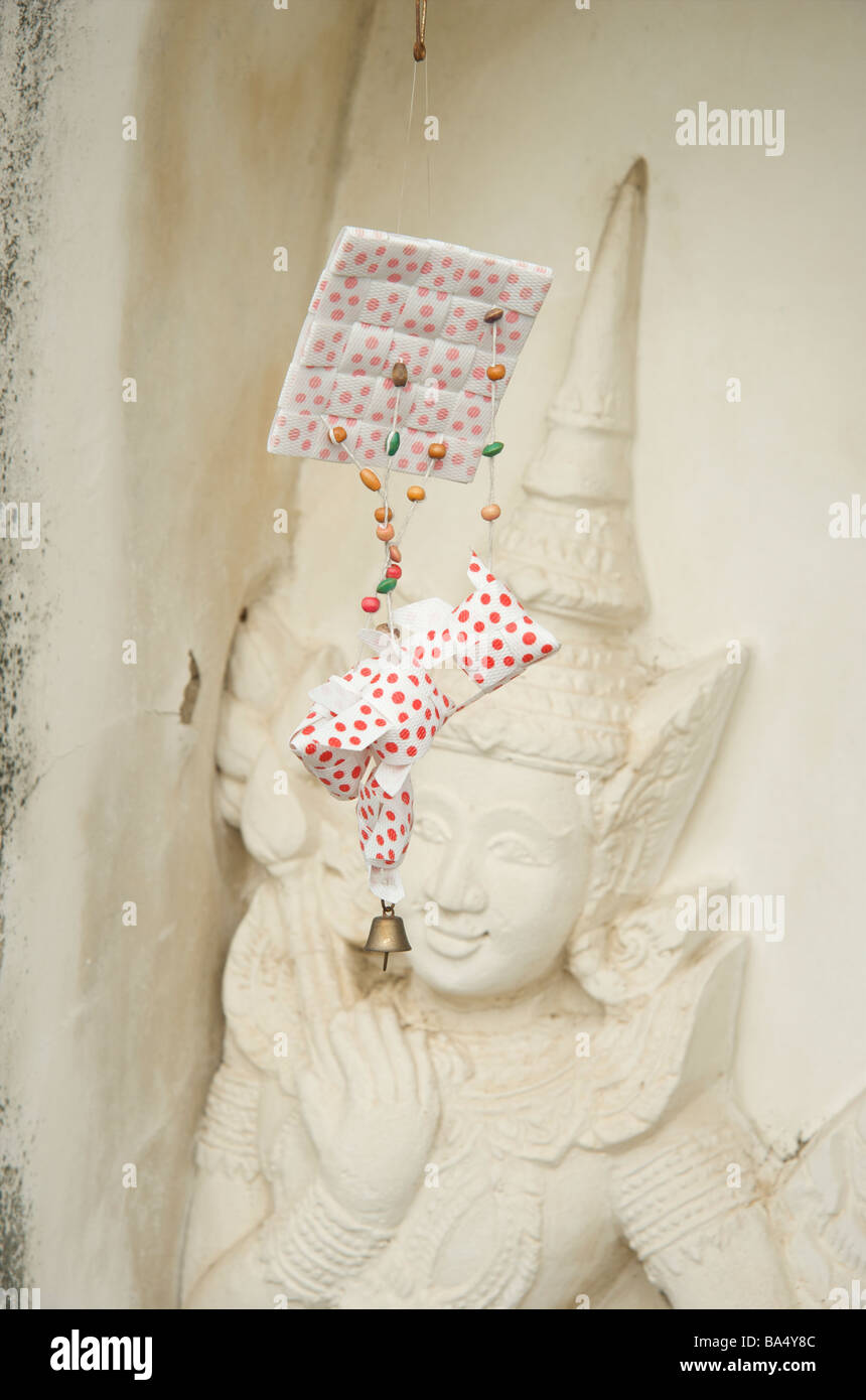 Un papier rouge offrant est en face d'une sculpture murale du temple à Bangkok Banque D'Images