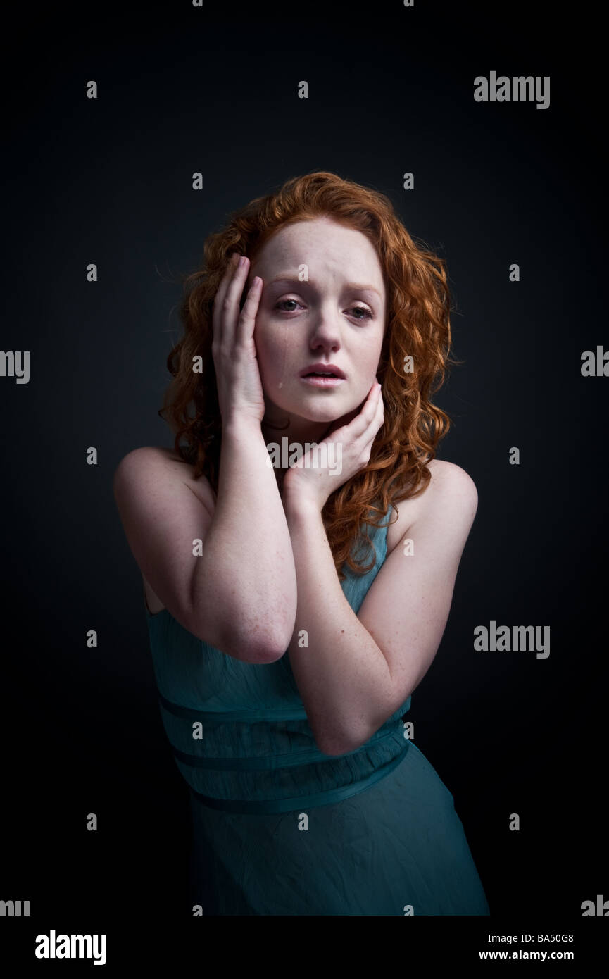 Red haired woman girl triste à pleurer seul Royaume-Uni, à la colère en larmes, tenant sa tête dans ses mains Banque D'Images