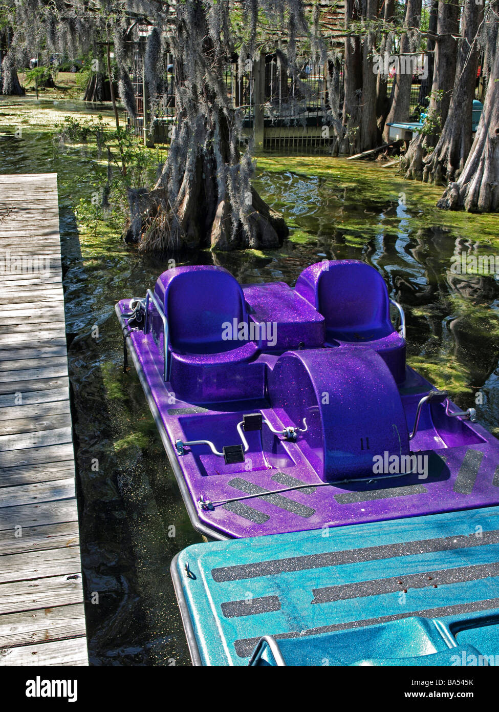 Peddlewheel ou peddle bateau bateaux volant violet et bleu lumineux avec des surfaces métalliques liés à quai à un lac prêt pour de l'amusement Banque D'Images
