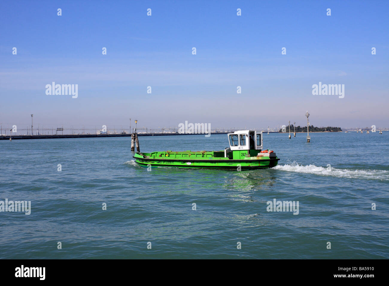 Bateau vert motoring à travers l'eau libre dans la lagune, Venise, Italie. Banque D'Images