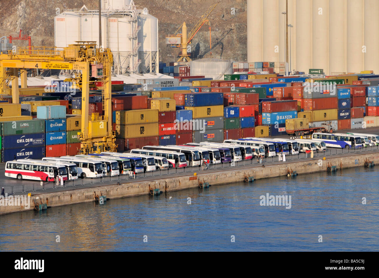 Des autocars d'excursion attendent les passagers des bateaux de croisière dans des conteneurs commerciaux Port Sultan Qaboos Muttrah Muscat Oman dans le golfe d'Oman Moyen-Orient Banque D'Images