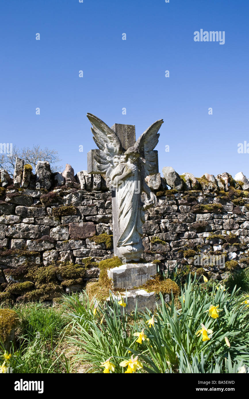 Angel pierre tombale en arrière-plan de cimetière contre mur de pierres sèches et bleu ciel d'été Banque D'Images
