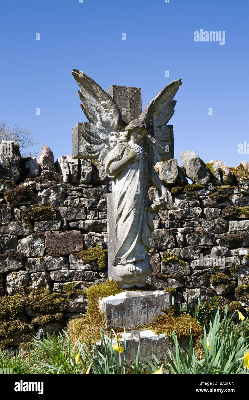 Angel pierre tombale en arrière-plan de cimetière contre mur de pierres sèches et bleu ciel d'été Banque D'Images