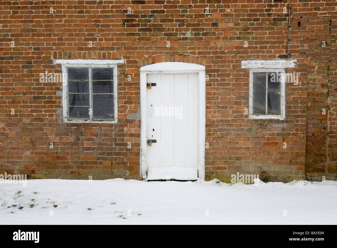 Porte et fenêtres d'une maison construite en brique abandonnés dans la neige Banque D'Images