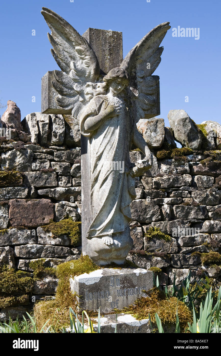 Angel pierre tombale en arrière-plan de cimetière contre mur de pierres sèches et bleu ciel d'été Banque D'Images