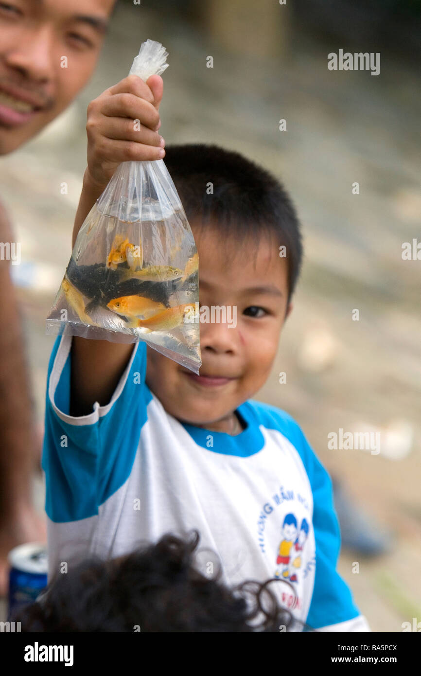 Les enfants vietnamiens titulaires d'un sac d'animal poisson pêché dans la rivière Saigon à Ho Chi Minh City Vietnam Banque D'Images