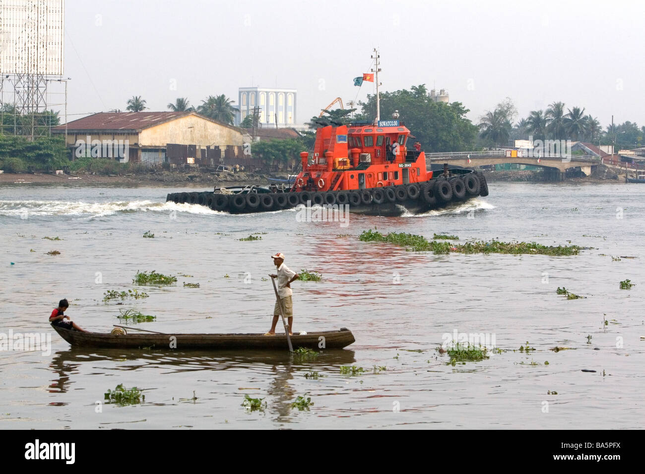 Sampan bateau en bois à fond plat et d'un remorqueur sur la rivière Saigon à Ho Chi Minh City Vietnam Banque D'Images
