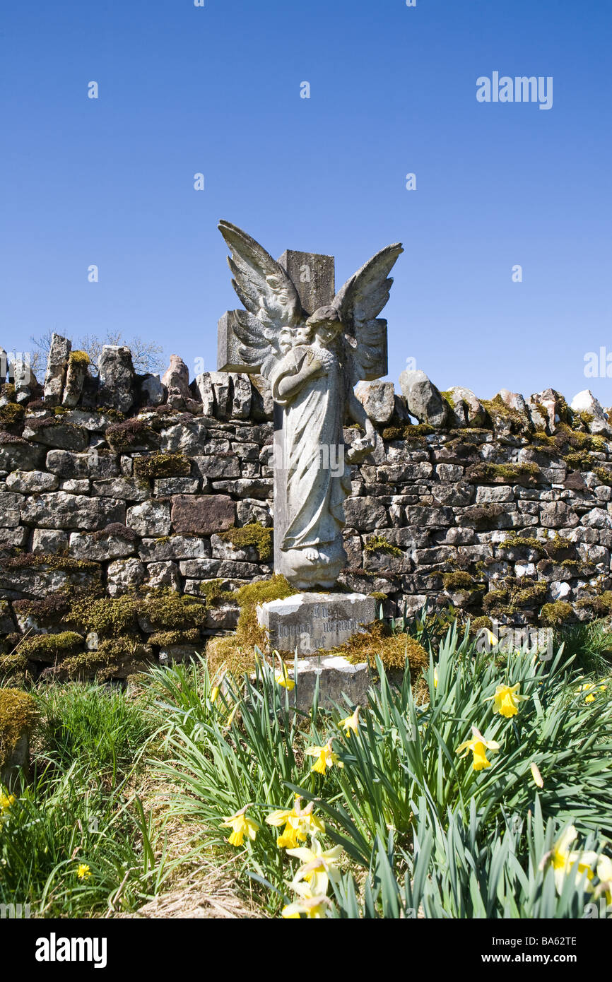 Angel pierre tombale en arrière-plan de cimetière contre mur de pierres sèches et bleu ciel d'été Banque D'Images