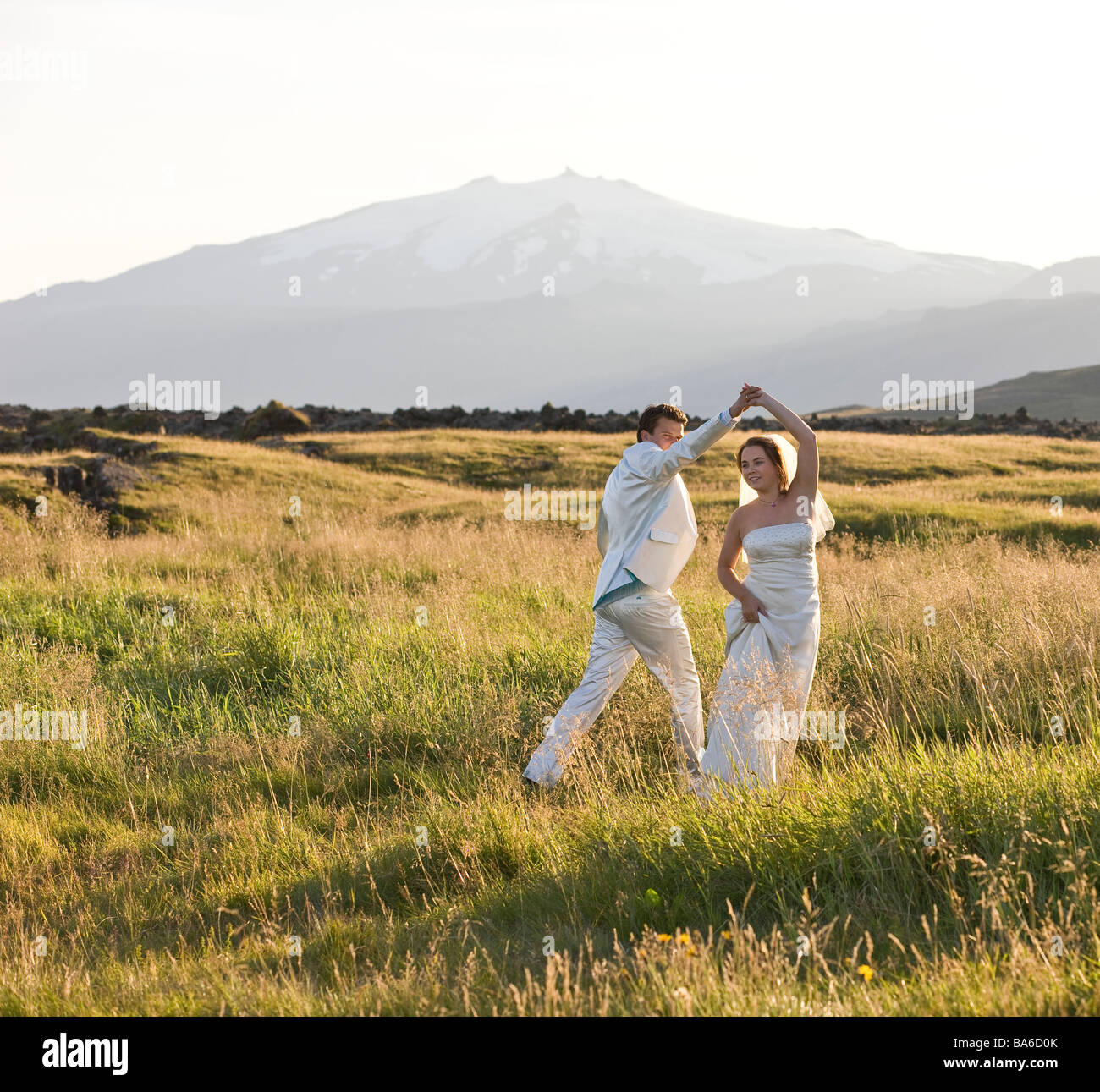Wedding couple danse de campagne avec glacier Snaefellsjokull en arrière-plan, l'Islande Banque D'Images