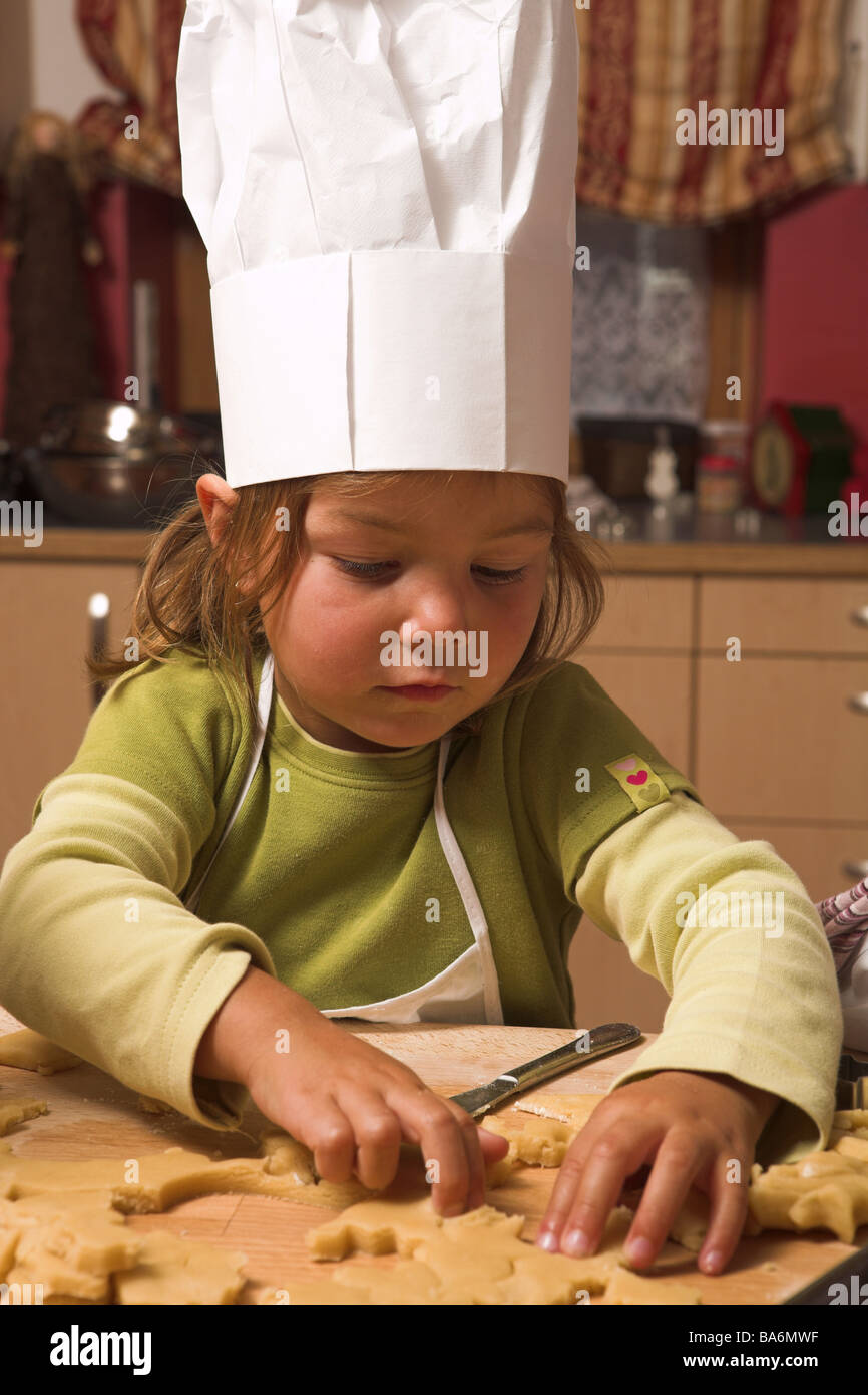Cuisine de Noël enfant filles gaiement la pâte cuit le portrait des lieux à l'époque de Noël gouges avènement 4 ans couvre-chef cuisinier-cap Banque D'Images