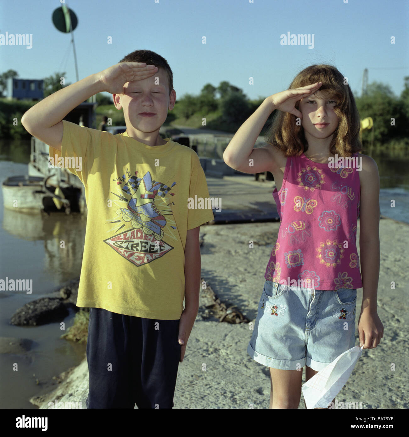 Pologne Tarnow river Dunajez pier garçon filles-militaire geste saluer les gens 9-10 ans les enfants de la petite enfance joue un chiffon de tissu Banque D'Images
