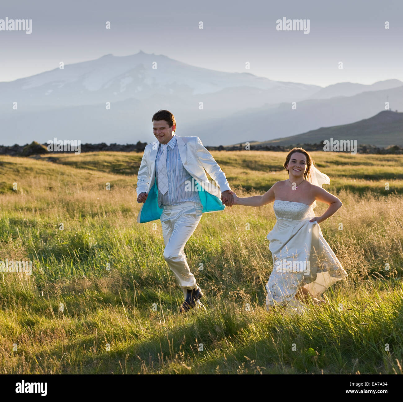 Couple fonctionnant en campagne, Glacier Snaefellsjokull en arrière-plan, dans l'ouest de l'Islande Banque D'Images