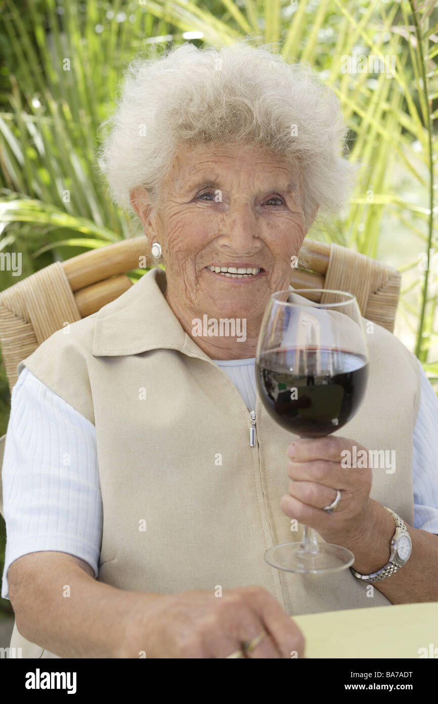 La haute terrasse en verre de vin rouge semi-sourire série portrait de personnes seniors femme 70-80 ans aux cheveux gris-blanc caméra regard brun Banque D'Images